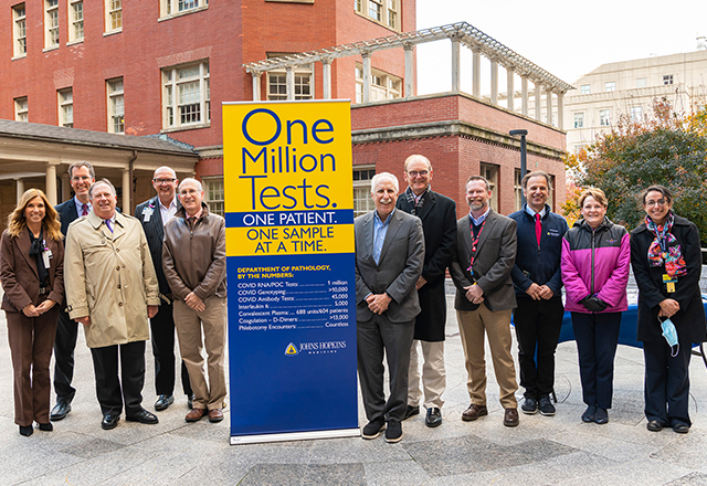 Rothman and his colleagues stand with a banner bug commemorating the 1 millionth vaccine. 
